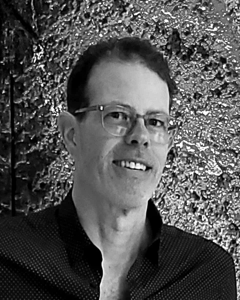 Louis Tremblay, souriant, devant une sculpture de la Maison Alcan